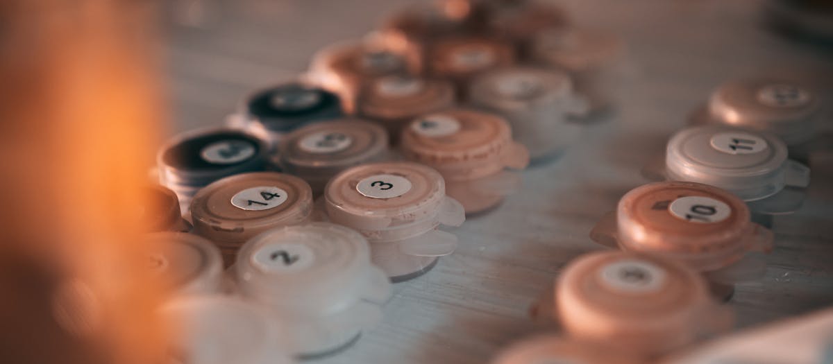 Artistic close-up of numbered paint pots on a table, ideal for painting by numbers enthusiasts.