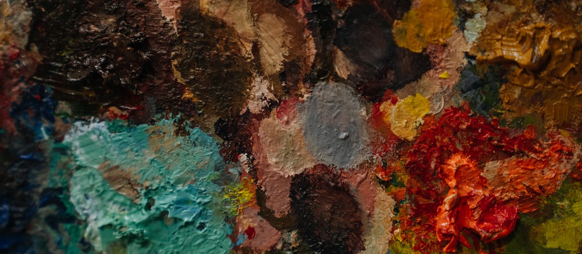 Close-up of a colorful artist's palette with various paint blobs and textures.