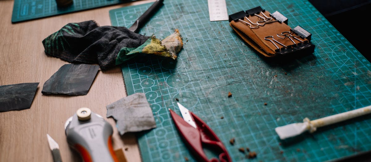 A cluttered workspace featuring cutting mats, tools, and crafting materials for DIY projects.